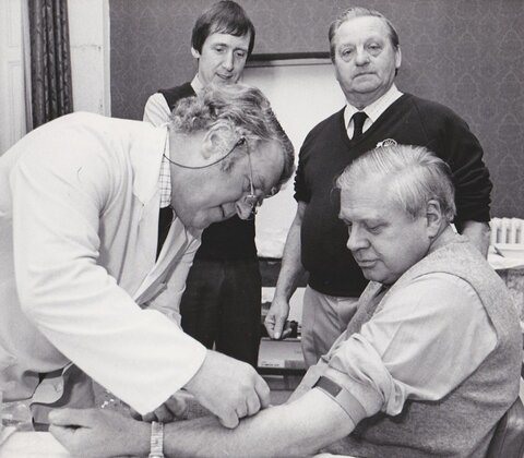 Dr Gill (rear left) observes as Dr Bell takes blood from FEPOW Bernard Sayles during a FEPOW meeting in Scarborough in 1979